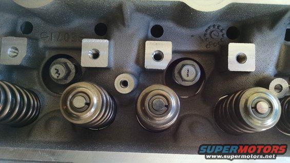 Close-up of an engine cylinder head showing valve springs and bolts. Text '61703' is visible