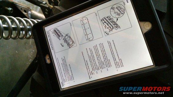 Tablet displaying engine repair manual with diagrams and text