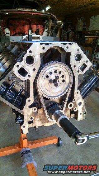 Engine block with timing chain and gears visible, on an orange stand