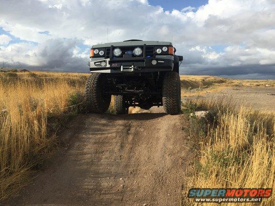 Front view of lifted off-road vehicle with ARB winch bumper and large tires on a dirt track