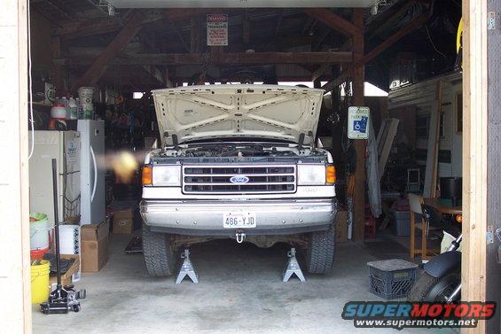 White 1990 Ford Bronco front view, hood open, on jack stands