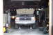 1990 Ford Bronco - A white 1990 Ford Bronco is parked in a garage with its hood open and front end raised on jack stands.