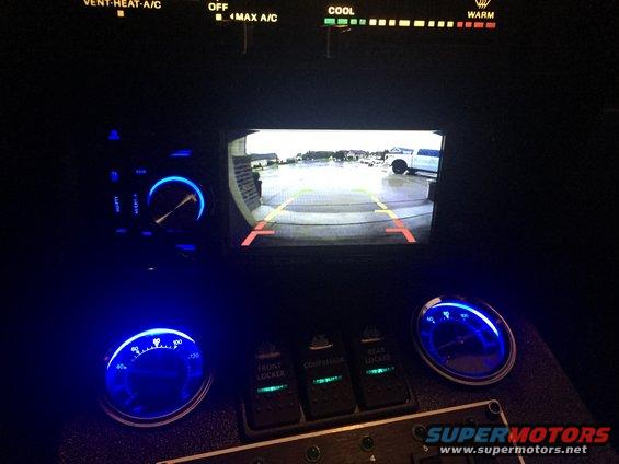 Interior view showing backup camera display with two vehicles visible outside