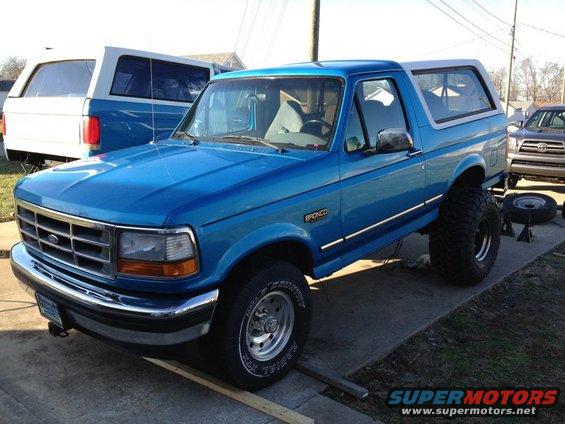 Blue 1995 Ford Bronco with lifted suspension and large tires parked next to another SUV