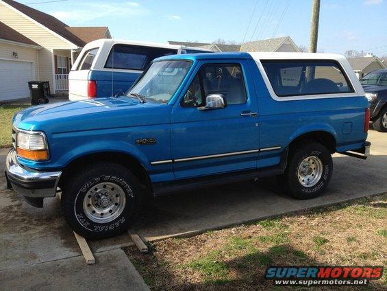 Blue 1995 Ford Bronco with a white top parked next to another Bronco