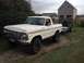 1979 Ford Bronco - A white 1979 Ford Bronco is parked on a dirt path, towing a trailer with a grill and cooler.