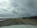 1979 Ford Bronco - Vehicles drive along the beach, leaving tire tracks in the sand under a dramatic sky.
