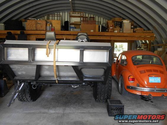 Orange Volkswagen Beetle with license plate BGB 575 parked next to a custom trailer
