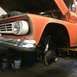 1962 Chevrolet Suburban - Front end of an orange pickup truck undergoing suspension work, hood is open.