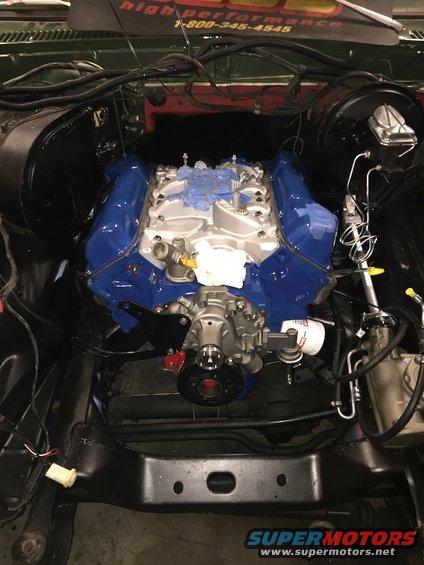 Engine bay with a blue V8 engine, oil filter, and various hoses and wires