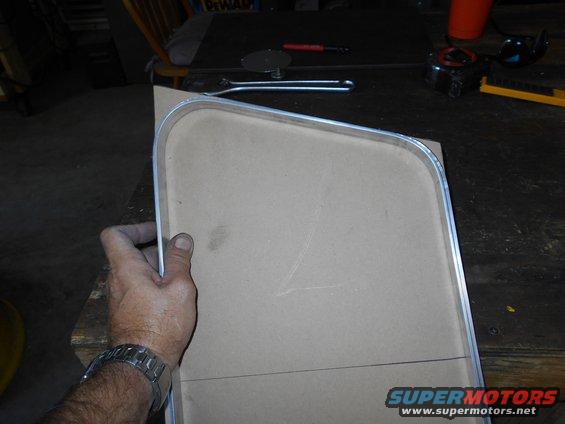hand holding cardboard template with metal trim, pencil lines drawn on it