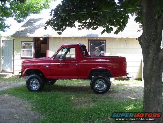 Red Ford Bronco parked in front of a house. It has a lifted suspension and off-road tires