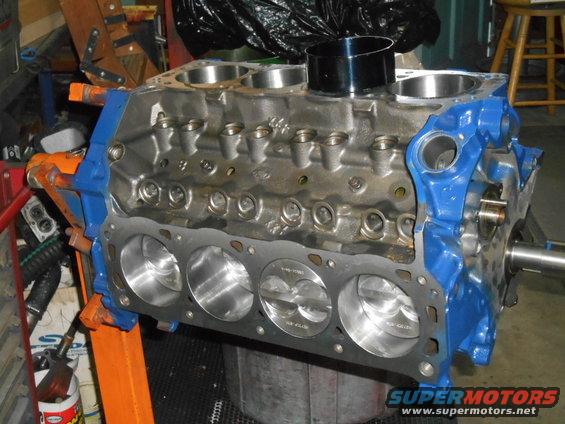 Ford V8 engine block with pistons, blue painted end caps, on an orange engine stand