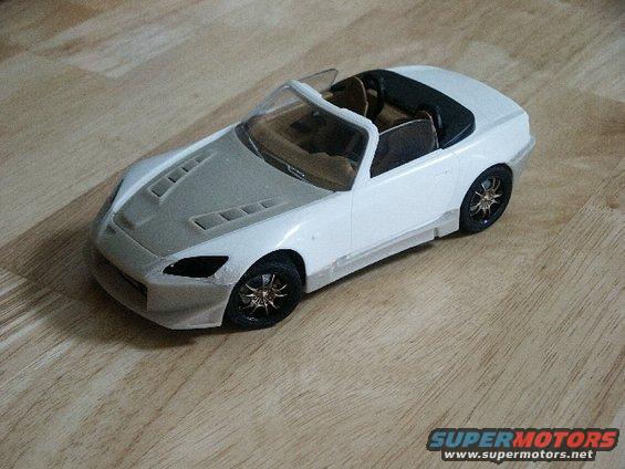 Model car with a white body and gray hood, sitting on a wooden surface
