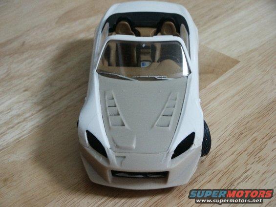 White model car front view with tan interior and hood vents