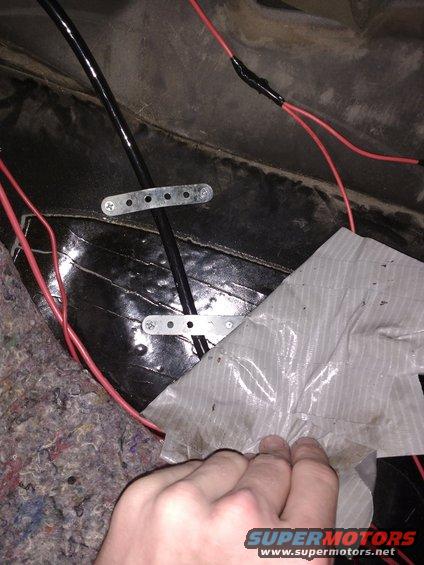 Main power cord strapped down under passenger carpet.