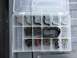 1988 Ford Bronco - A clear plastic organizer contains a collection of automotive hardware, including bolts, nuts, and metal clips.