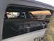 1988 Ford Bronco - A black storage box is visible inside a vehicle, with another vehicle seen through the window at sunset.