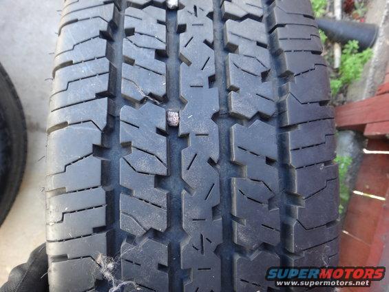 Tire tread with a nail embedded in it, close-up view