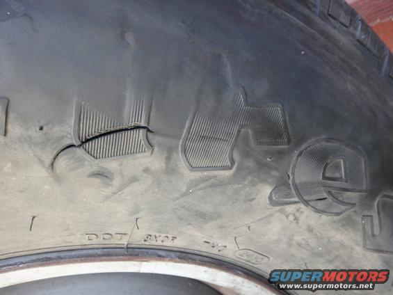 Close-up of damaged tire tread with visible DOT markings