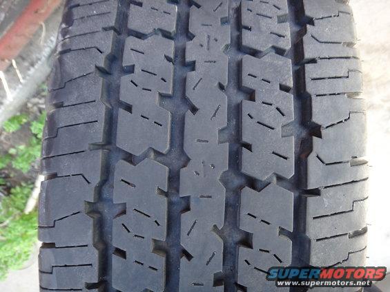 Close-up of a tire tread pattern with the "SUPERMOTORS.NET" watermark visible