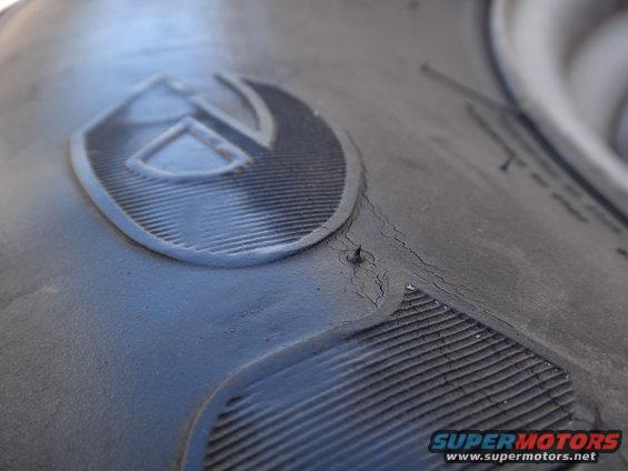 Tire with a shield-like logo and tread detail. Supermotors.net watermark visible