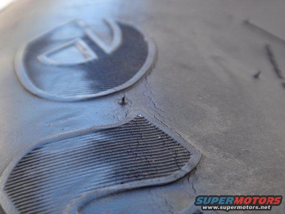 Close-up of a tire tread showing a brand logo and cracking rubber