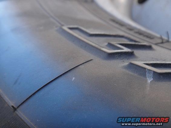Close-up of tire tread with raised blocks and a curved line