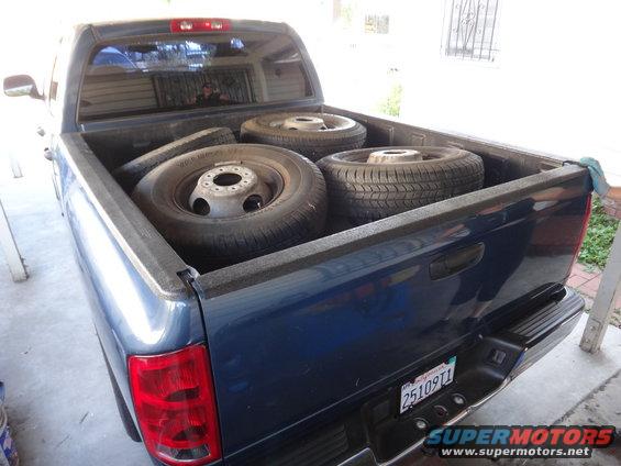 Blue pickup truck bed loaded with four tires and wheels