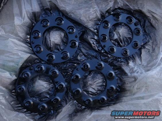 Four black wheel spacers with multiple bolt holes