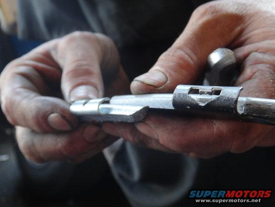 Metal linkage part being held and worked on by hands