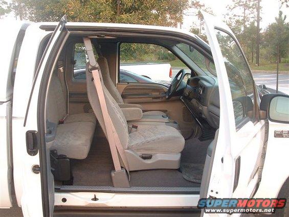 Interior of a white pickup truck with open doors, showing front and rear seats