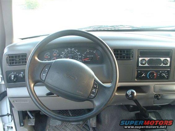 Dashboard view of a 1999 Ford F-250 Super Duty truck, showing the steering wheel, instrument cluster, and center console with radio and climate controls