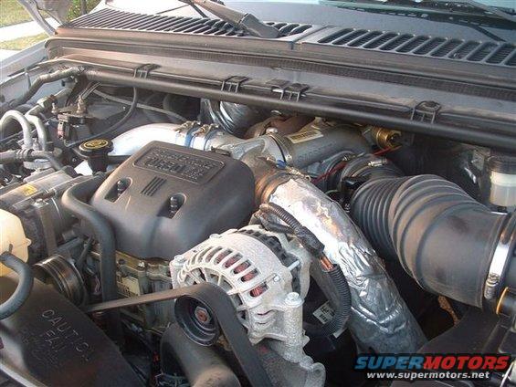 Engine bay with "TURBO DIESEL" cover, alternator, and intake piping
