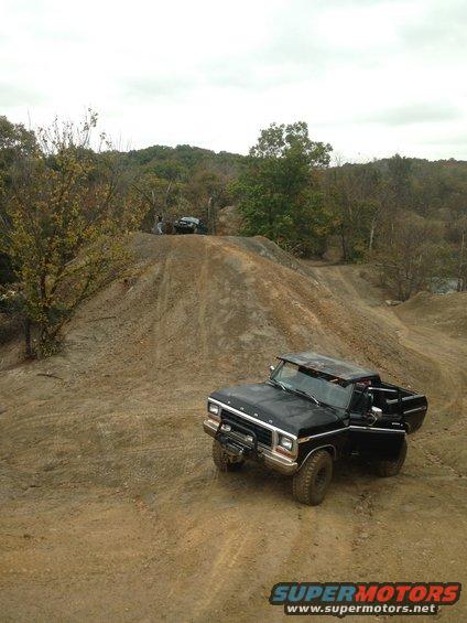 Black 1980s Ford F-Series truck on dirt hill, another vehicle in background