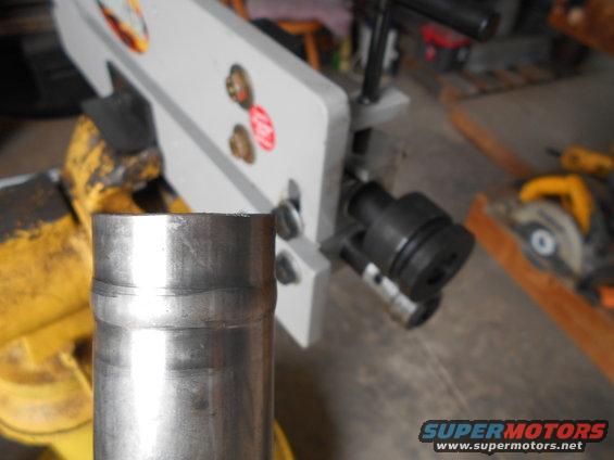 metal pipe in foreground, pipe bender behind it, circular saw on right