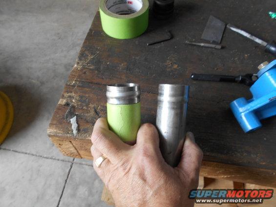 Two metal cylinders, one taped green, on workbench with tools