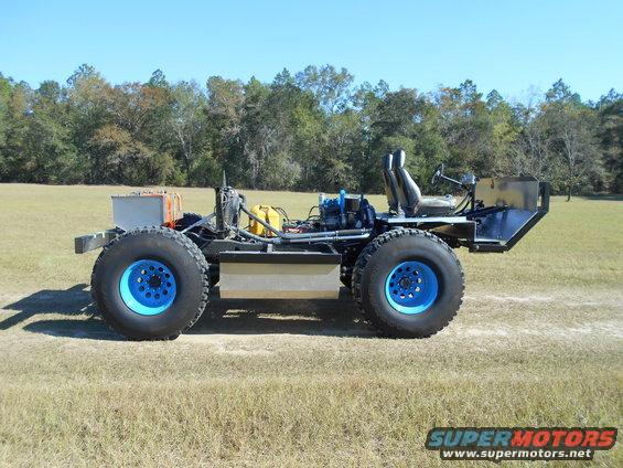 Custom off-road vehicle with large blue-rimmed tires, exposed engine, and two seats