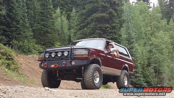 1996 Ford Bronco with aftermarket bumper and lights on a dirt road