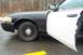 2001 Ford Crown Victoria - The side profile of a black and white 2001 Ford Crown Victoria police car, with the driver's door ajar.