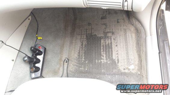 Interior car floor with water stains and a power adapter plugged into a car charger