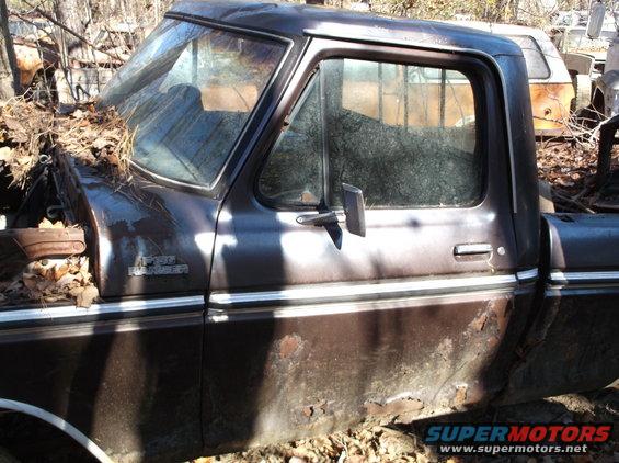 Side view of a rusty brown 1975 Ford F-150 Ranger pickup truck with leaves covering the hood
