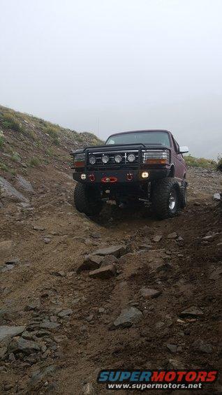 Dark red 1996 Ford Bronco with bull bar and off-road tires on a rocky trail