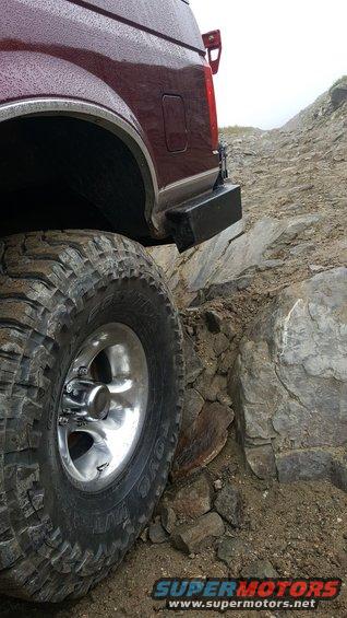1996 Ford Bronco rear quarter panel and large off-road tire navigating rocks