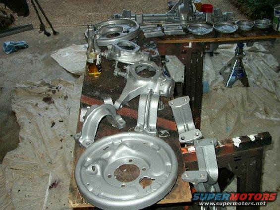 Silver painted suspension parts and brake drum on a workbench