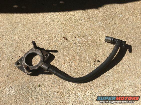 Automotive part with a metal flange and two black hoses attached