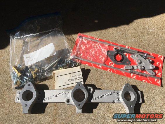 Offenhauser intake manifold with hardware in plastic bags and red packaging on concrete