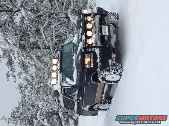 Black 1996 Ford Bronco with light bar covered in snow