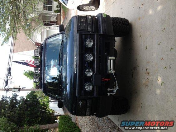 Black SUV with a light bar on top, winch on the front bumper, and large off-road tires