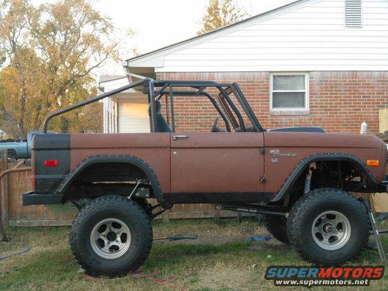 Brown 1972 Ford Bronco side view with roll cage and lifted suspension